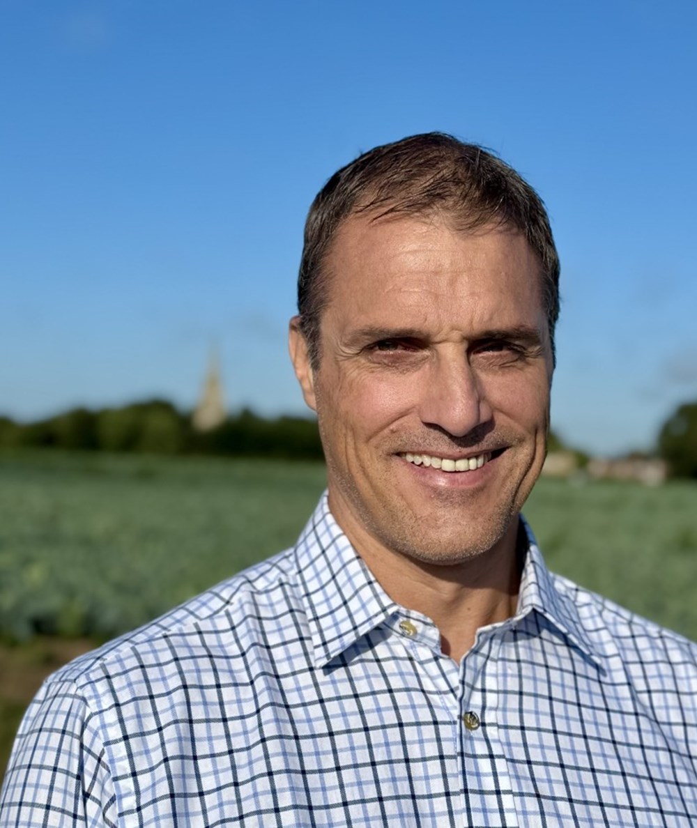 Close up of a man, Mark Haighton, with a field in the background.